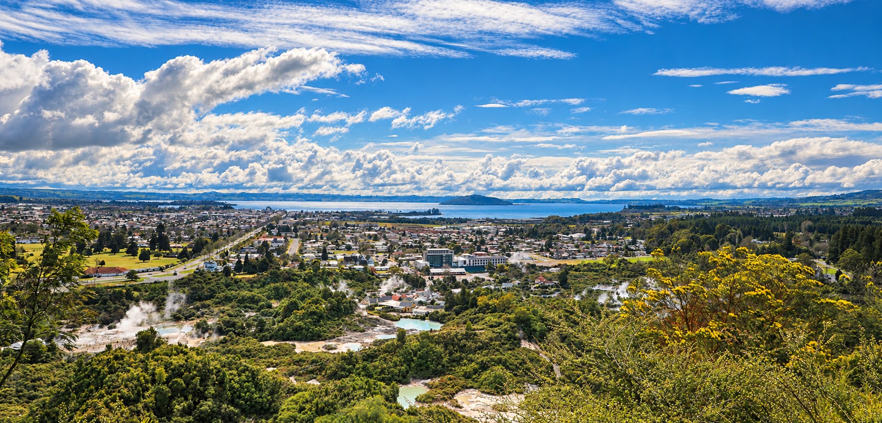 Panorama of Rotorua with geothermal steam and the lake beyond